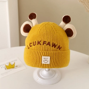 Detail of yellow knit baby beanie featuring 3D brown antlers and embroidered letters