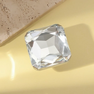 Exaggerated square cut crystal ring with silver metal claw setting on stone background