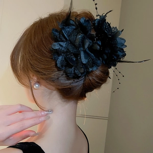 Detailed close-up of elegant black floral hair claw with feathers and bead strands