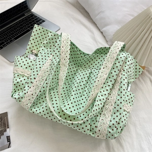 Detail of mint green polka dot tote bag with lace trim on a cozy white bed setting