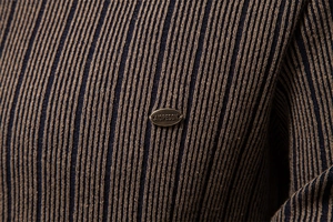Macro shot of vertical ribbed knit texture with decorative metal brand plate detail