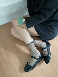 Detail of lettuce edge cuffs and heart pattern on beige crew socks with Mary Jane shoes