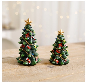 Set of two resin Christmas trees with gold stars and festive ornaments on wood