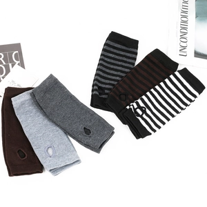Flat lay of striped and solid knitted fingerless arm warmers with thumb holes