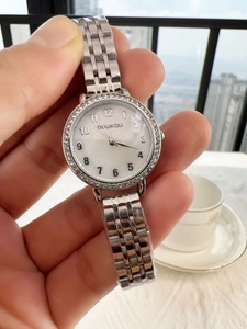 Detailed shot of a silver women's watch featuring a diamond bezel and metal band