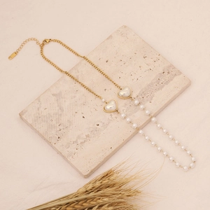 Close-up of gold heart pendant necklace with pearls on a textured stone surface