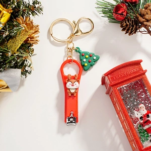 Christmas reindeer nail clipper keychain with Santa tree charm on festive pine background