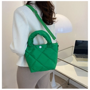 Detail of green quilted handbag featuring a puffy ruched handle and adjustable strap