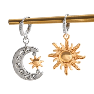 Détail de boucles d'oreilles asymétriques lune et soleil aux tons or et argent avec zircon