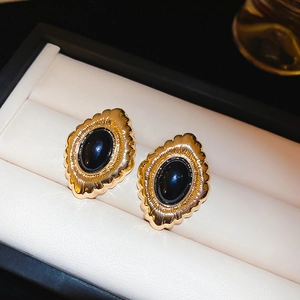 Close-up of vintage oval black gemstone earrings in a gold-plated flower setting