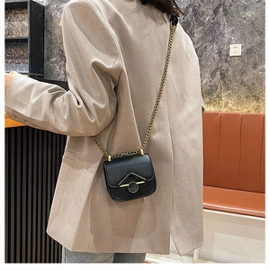 Dettaglio di una mini borsa a tracolla in pelle nera con catena dorata su modella