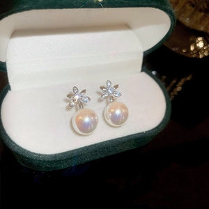 Macro detail of silver floral stud earrings with iridescent pearl in a green velvet box