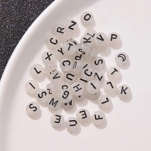 Detailed view of luminous alphabet beads in a white bowl for DIY jewelry making