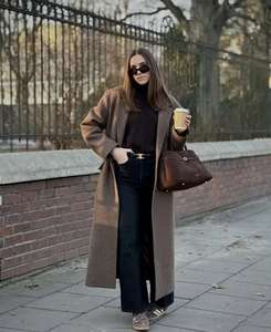 Street style shot of a long dark brown wool coat paired with black wide-leg trousers