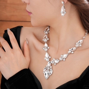 Primo piano di collana e orecchini in strass argentati a goccia indossati da modella