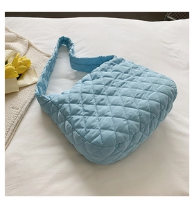 Detail of light blue quilted cloud bag with diamond pattern on white fabric texture