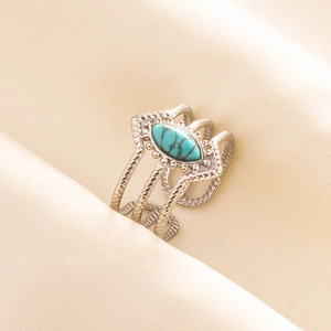 Macro detail of multi-layered silver ring with oval turquoise stone on beige fabric