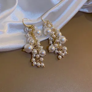 French retro pearl tassel drop earrings with elegant gold hooks on white silk fabric