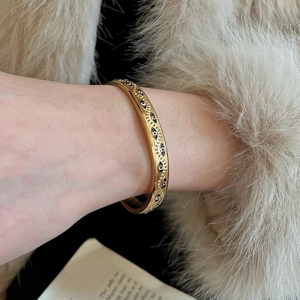 Détail d'un bracelet jonc doré œil protecteur avec relief sur fond en fausse fourrure