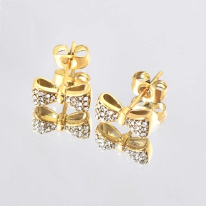 Detailed view of gold bow earrings with sparkling white crystals and mirror reflection
