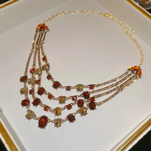 Detail of luxury vintage layered necklace with amber and red gemstones in a white jewelry box