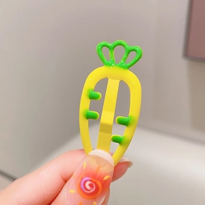 Close-up of cute carrot-shaped hair clip in bright yellow and green candy colors