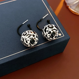 Close-up of leopard print round stud earrings placed on a deep blue gift jewelry box