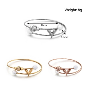 Dettaglio del ciondolo a V sul bracciale rigido in filo d'acciaio in oro, argento e rosa