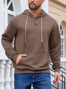 Macro detail of brown knitted jacquard texture and buttoned collar on men's hoodie