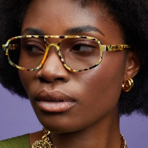 Close-up of retro aviator sunglasses with colorful marbled frames on a model