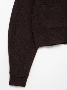 Detail of dark brown knitwear showing premium wool texture and ribbed cuffs and hemline