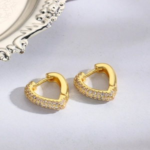 Macro shot of gold heart-shaped hoop earrings with pave-set sparkling zircons