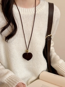 Brown flocked heart pendant on a fine cord worn over a chunky knit sweater