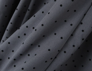 Detailed macro view of dark grey fabric with black polka dots and fine twill texture