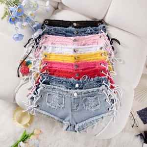Dettaglio di pantaloncini di denim a vita bassa con lacci laterali e bordi sfrangiati