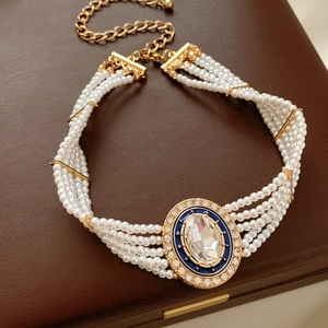 Detail of multi-layer pearl necklace with blue enamel oval crystal pendant on leather