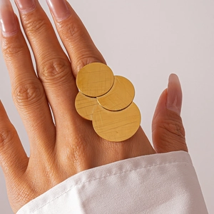 Detailed view of large golden brushed metal multi-disc statement ring on a female model
