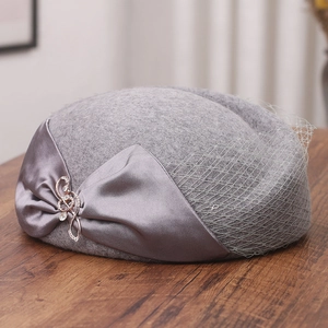 Detail of grey wool pillbox hat with satin bow, rhinestone buckle and delicate mesh veil