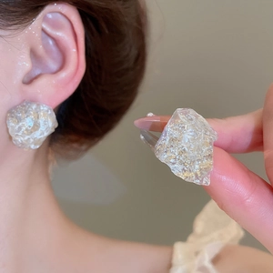 Detailed view of irregular resin earrings with gold foil inlay on a model's ear