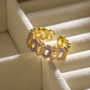 Macro view of gold plated geometric ring with purple enamel and white zircon inlay