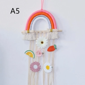 Detail of woven rainbow wall hanging with pink flowers and crochet carrot decor