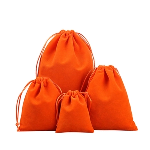 Set of four orange velvet drawstring gift pouches in various sizes on white background