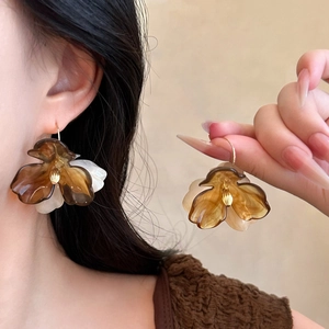 Detailed view of bohemian acrylic flower tassel earrings with amber and cream petals