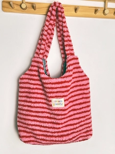 Close-up of a pink and red striped lamb wool plush tote bag hanging on a wooden rack