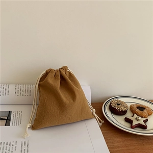 Detail of a brown drawstring storage bag with natural texture on a cream background