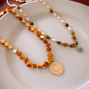 Detailed macro of vintage layered necklaces with oval tiger eye and turquoise pendants