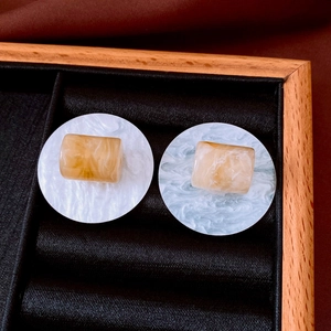 Gros plan de boucles d'oreilles en résine ambre avec détails de texture marbrée