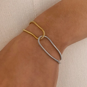 Two-tone gold and silver U-shaped clasp snake chain bracelet on female wrist