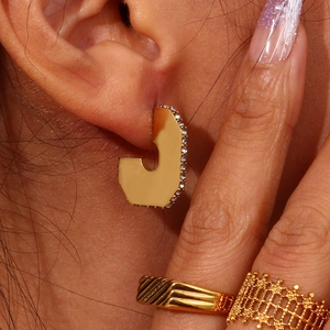 Close-up of golden irregular earrings with micro-set zircons and matching rings
