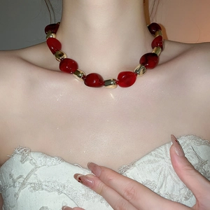 Close-up of irregular red acrylic beads and gold metal links on a vintage style necklace